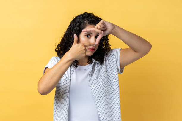 istock Woman making frame gesture with her fingers as she looks through camera, composition of photograph. 2107681305