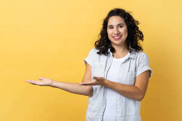 istock Woman showing welcome gesture and empty space on wall for your best advertising. 2107681315