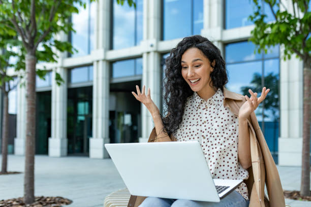 istock Young businesswoman using laptop outside modern office building 2107690888