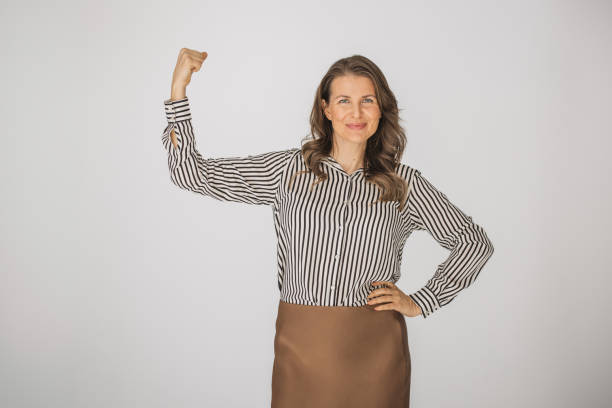 Studio shot of a young businesswoman standing with his fists raised in celebration against a gray background
