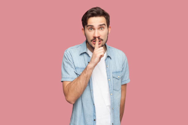 istock Stupefied man standing makes gesture quietly, asks remain silent, gossips about something. 2107691977