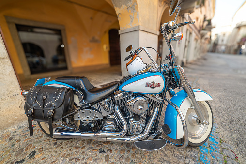 Savigliano, Cuneo, Italy - March 21, 2024: Harley Davidson custom motorcycle parked on cobblestones of historic downtown street