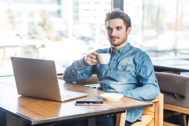 istock Calm handsome man freelancer working on laptop, watching presentation and drinking coffee. 2107702687