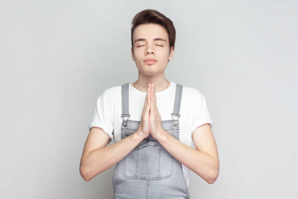 istock Man standing holding hands in namaste or prayer, keeping eyes closed while practicing yoga. 2107705842