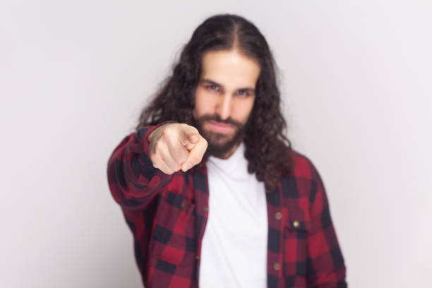 istock Displeased man in checkered red shirt blames someone, points directly at camera, makes serious face. 2107705855