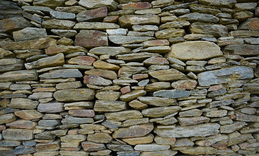 Old traditional aged and cracked stone wall made with large stone blocks