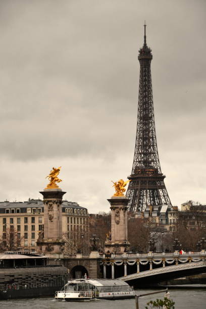 We can see on the foreground the Seine with riverboats, and the Alexandre III bridge. On the background we can see the Eiffel tower.