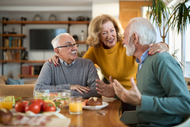 istock Group of happy senior friends talking while having a meal at dining table. 2107777439