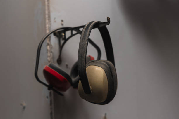 closeup Ensure workplace safety with this image featuring two pairs of ear protection headsets hanging neatly on the wall of a workshop. The presence of these essential safety gears underscores the importance of protecting one's hearing in noisy work environments, promoting a culture of safety and responsibility