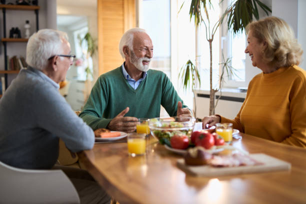 istock Group of happy senior friends talking while having a meal at dining table. 2107807317