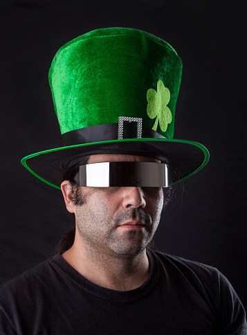 young man with St Patrick hat and cyber futuristic glasses on black background