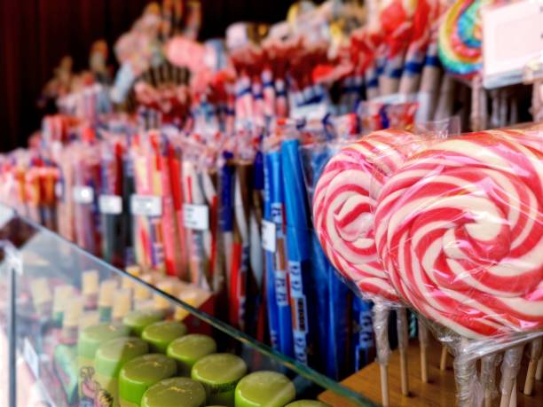 istock Detailed shot of red white round lollipops that are lined up in a row between candy canes and other candy in a candy stall at the fun fair 2107940708