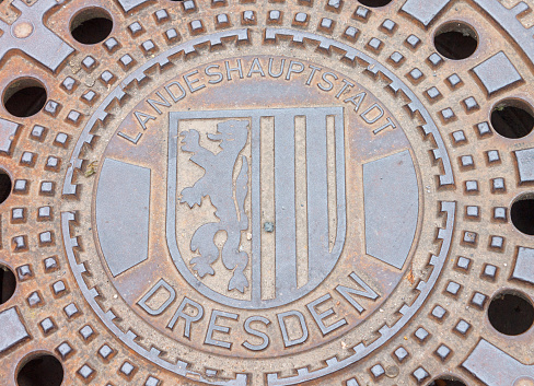 The coat of arms of Dresden, Saxony, Germany with a lion in bas relief on a manhole.