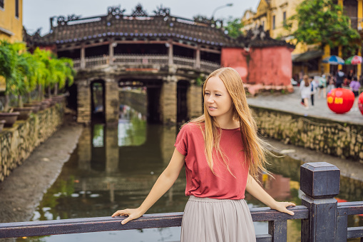 Woman tourist on background of Beautiful Japanese Bridge in Hoi An. Vietnam. Vietnam opens to tourists again after quarantine Coronovirus COVID 19.