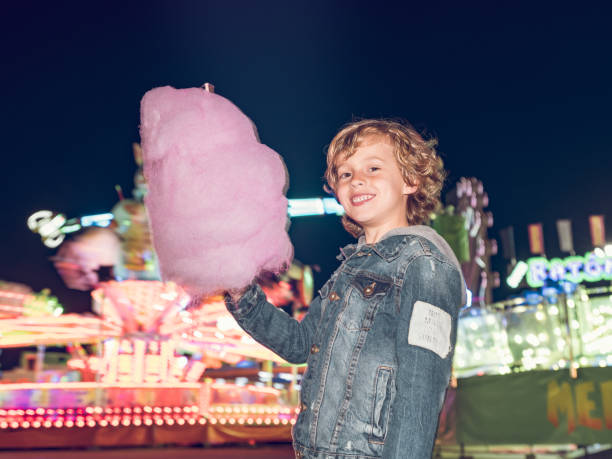 istock Cheerful boy with cotton candy in amusement park 2108068125