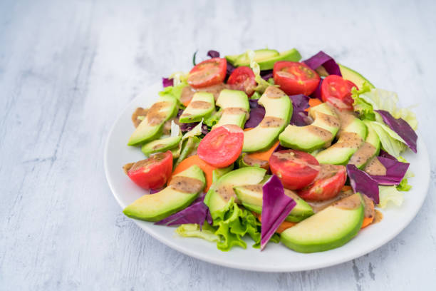 Cut avocado and a plate of avocado vegetable salad