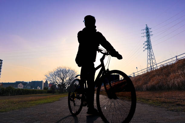 Silhouette man on a bike with head looking to the left side with beautiful sunset