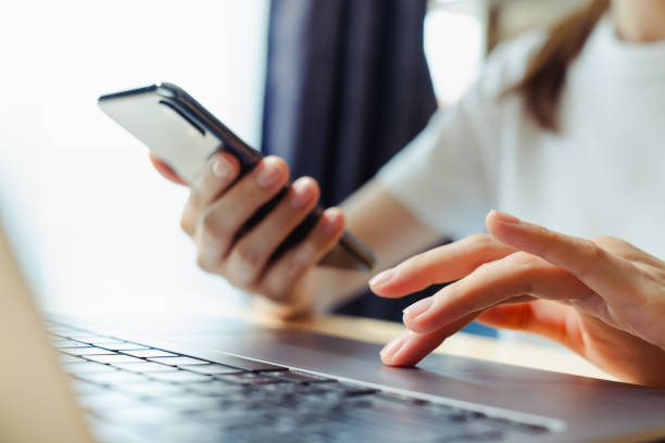 istock Woman using smartphone and hand typing on the computer keyboard in the office. 2108263094