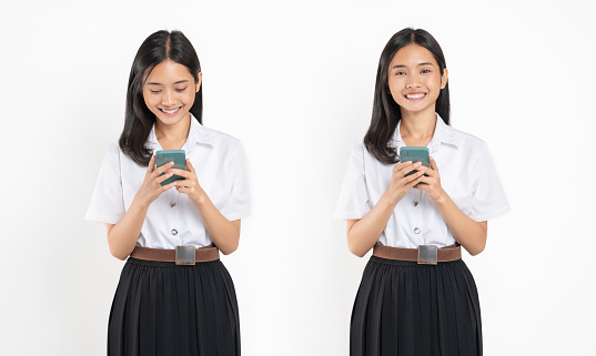 Smiling student girl in university uniform holding smartphone on white background.