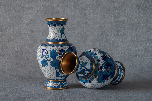Antique brass paired cloisonné enamel Chinese vases on a grey background.