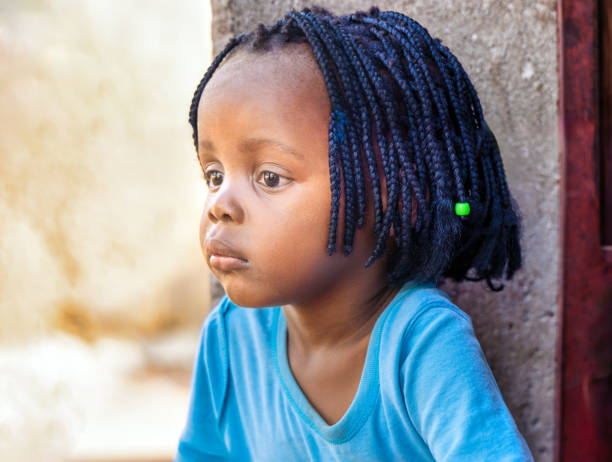 village african girl with braids in front of her home, sited on the veranda