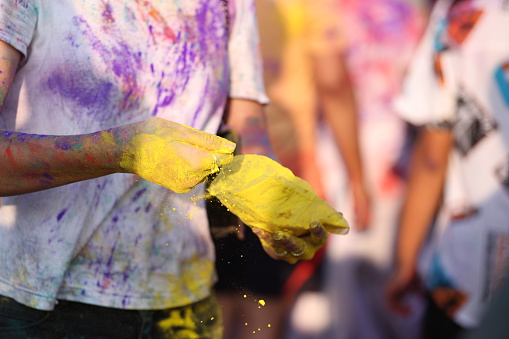 A young woman holding yellow powder in her hands at the Holi festival.