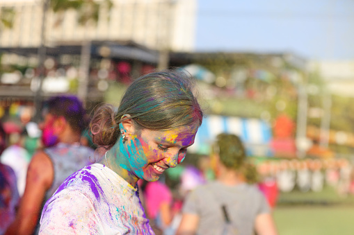 Portrait of a young foreign tourist joining the Holi festival, enjoying the colorful splashes, music, and dance, and experiencing Hindu Indian culture and lifestyle.