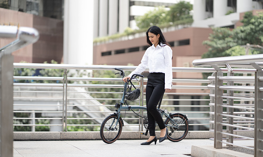 Eco friendly vehicle. 20s businesswoman ride bicycle to work in urban. Cycling has no pollution , alternative commute to global warming. Environmental preservation by sustainable energy with bicycling