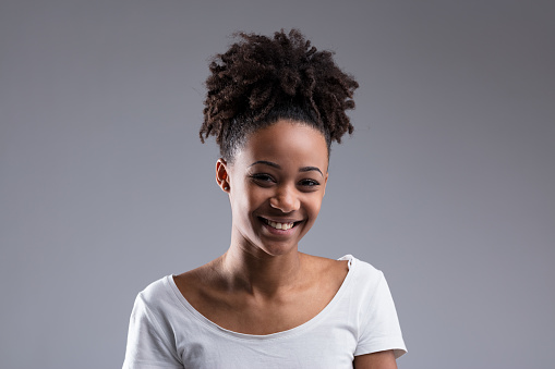 Radiant young woman smiling broadly in a casual white t-shirt, her hair styled in a natural updo
