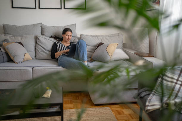 istock Woman scrolling through social media on mobile phone while relaxing on sofa at home 2108416892