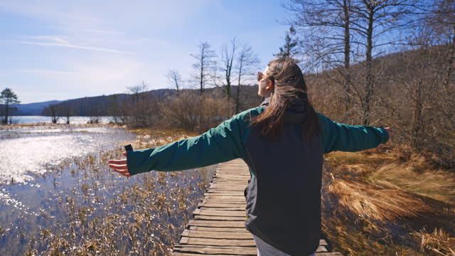 SLO MO Rear View of Young Female Tourist with Arms Outstretched Walking on Boardwalk at Plitvice Lakes National Park