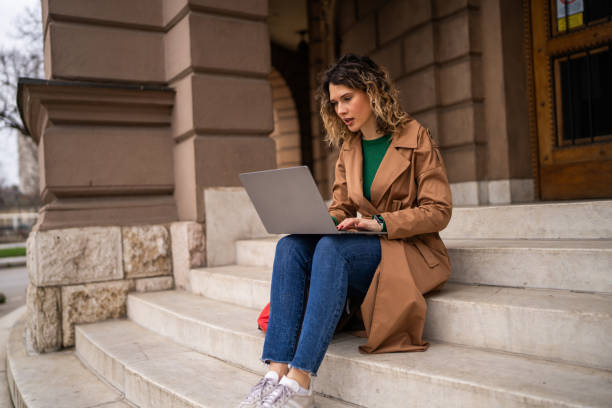 istock Female college student using a laptop on stairs 2108437137