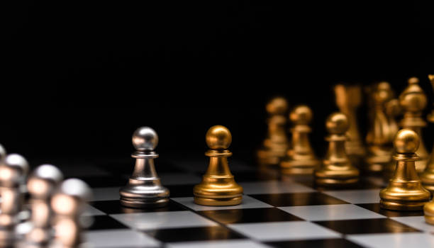 istock Focused pawn. Silver chess pieces and golden rivals. 2108564120