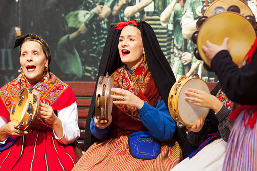 Women in a row playing  tambourines in the street, singing, wearing elegant historical clothing. Lugo city, Galicia, Spain during San Froilán autumn traditional celebrations.