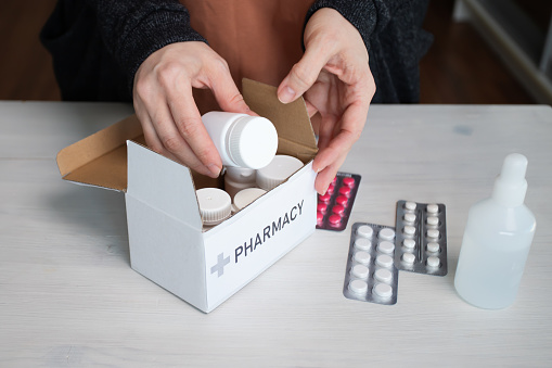 Home medicine delivery, woman with a box of pills, pharmaceutical care