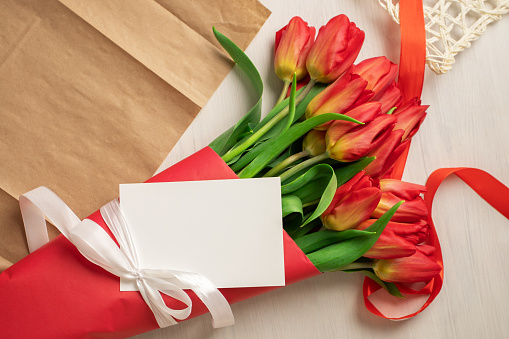 Fresh tulips with greeting card, springtime gift, nature-inspired decoration, floral composition.