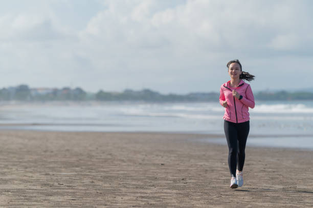 istock Asian Female jogging at beach 2108592105