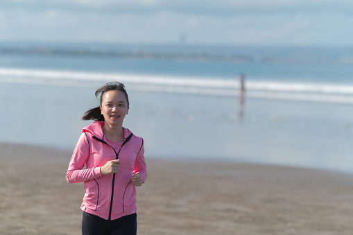Asian Female jogging at beach alone at morning