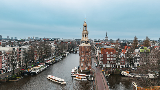 Aerial view of Montelbaanstoren Clock Tower in Amsterdam, Montelbaanstoren tower in Amsterdam, aerial city view of Montelbaanstoren Tower, aerial view of narrow canals of Amsterdam, popular place in Amsterdam

The Montelbaanstoren is a tower on bank of the Oudeschans – a canal in Amsterdam. The original tower was built in 1516 as part of the Walls of Amsterdam for the purpose of defending the city and the harbour. The top half, designed by Hendrick de Keyser, was extended to its current, decorative form in 1606. Since then the tower has been 48m tall.

Because the 3rd Duke of Alba proposed incorporating the tower into a castle (the Monte Albano) the tower became known in Dutch as the Monte Albano Toren. Over the years this became garbled to 