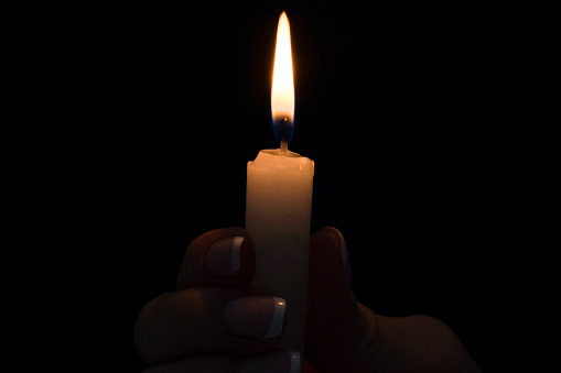 Burning candle isolated on black background. Copy space. Close up.