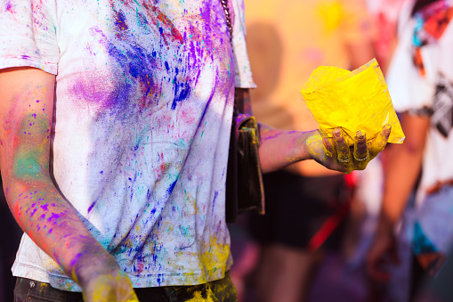 A girl with colorful holi powder splashed on her white T-shirt.