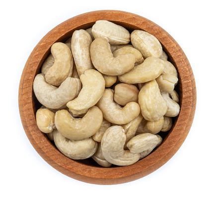 Top view of Roasted Cashew Nuts in wooden bowl isolated on white background. Peeled Cashew.