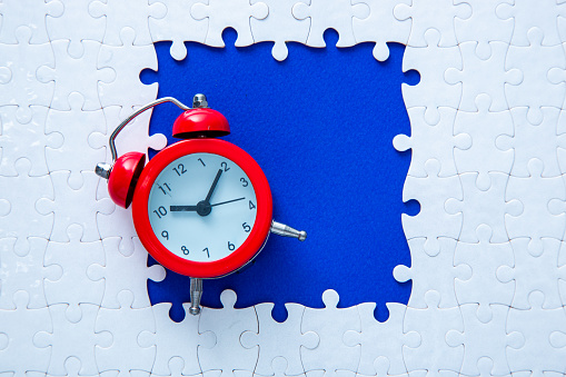 Red clock with white puzzle on blue background