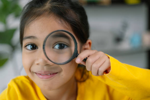 istock A young girl is holding a magnifying glass and looking at something 2108678651