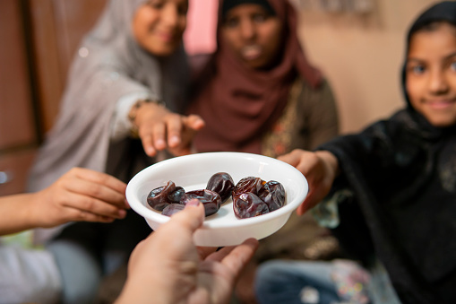 Close –up shot of Islamic family having iftar eating traditional dates fruits to break fasting during Ramadan month at home.