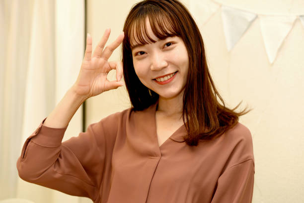 istock Young Asian woman doing OK pose indoors 2108693242