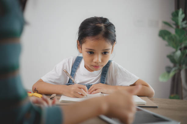 istock A young girl is sitting at a table writing in a notebook 2108696491