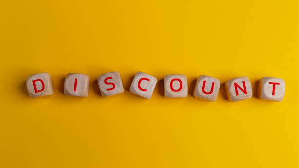 istock Text discount on a wooden cube on a yellow background. Sales discount concept, copy space 2108705957