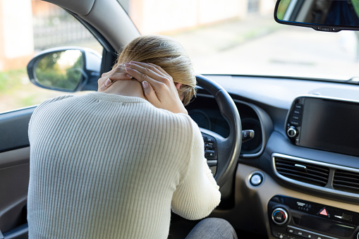 Woman suffering from neck pain in the car
