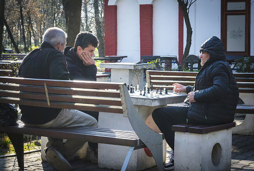 Pensioners relax in the park, playing chess. Romania, Gorj. March, 19, 2024